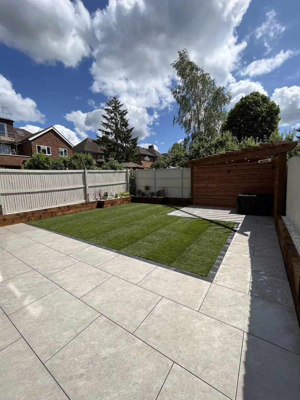 A lawn framed by pale paving and timber boundaries