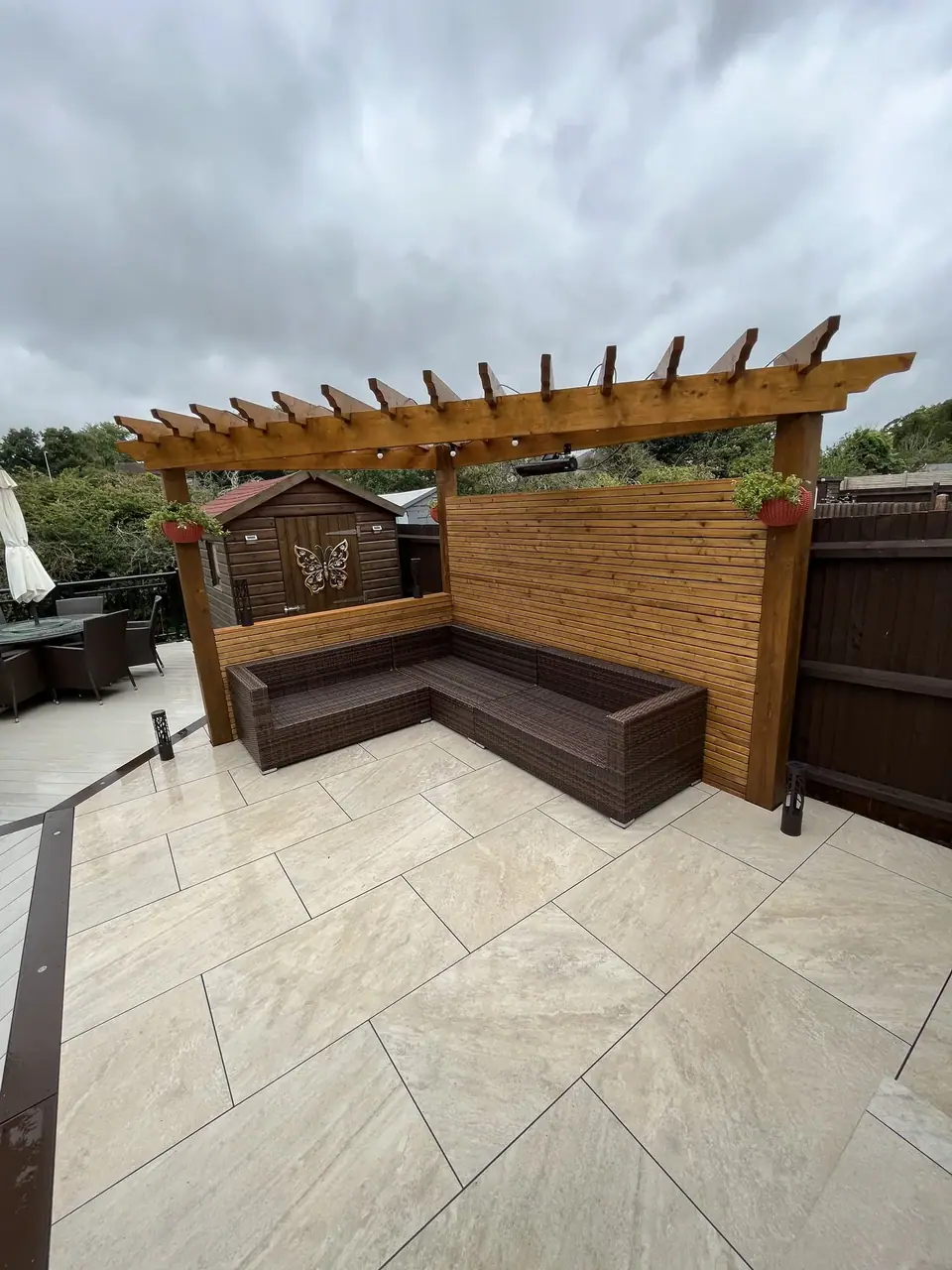 Timber pergola and seating beside pale paving and contrasting decking
