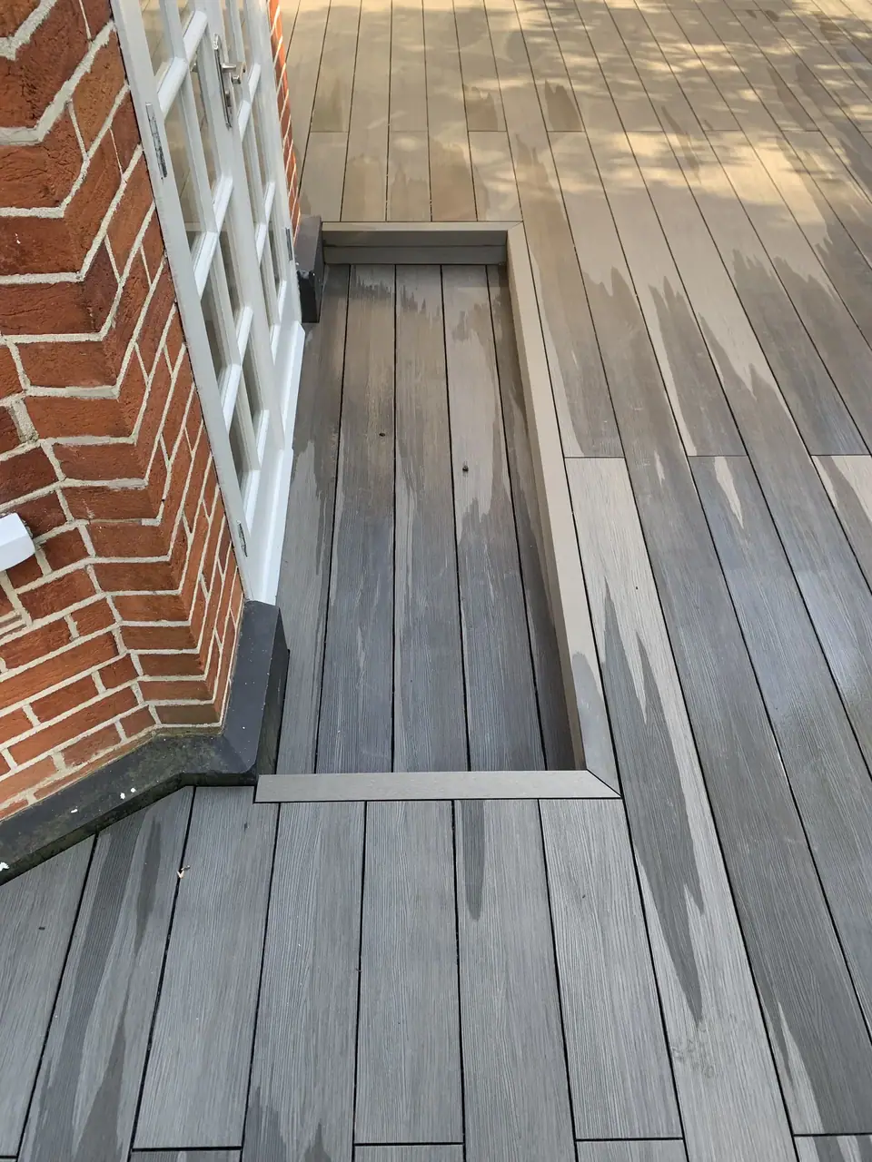 Close view of deck edges and steps against a brick house
