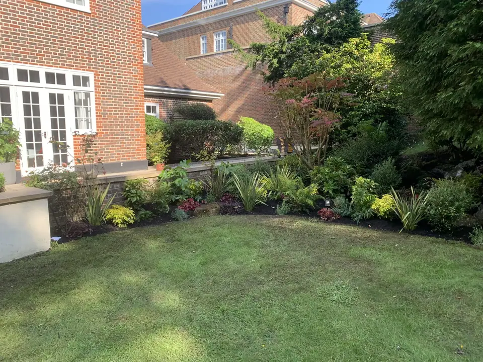A curved planted border beside a lawn and brick house