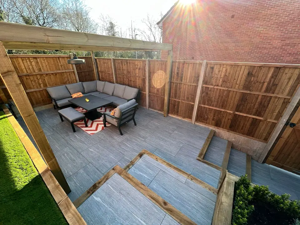 Timber pergola framing a sofa and table on a paved seating area
