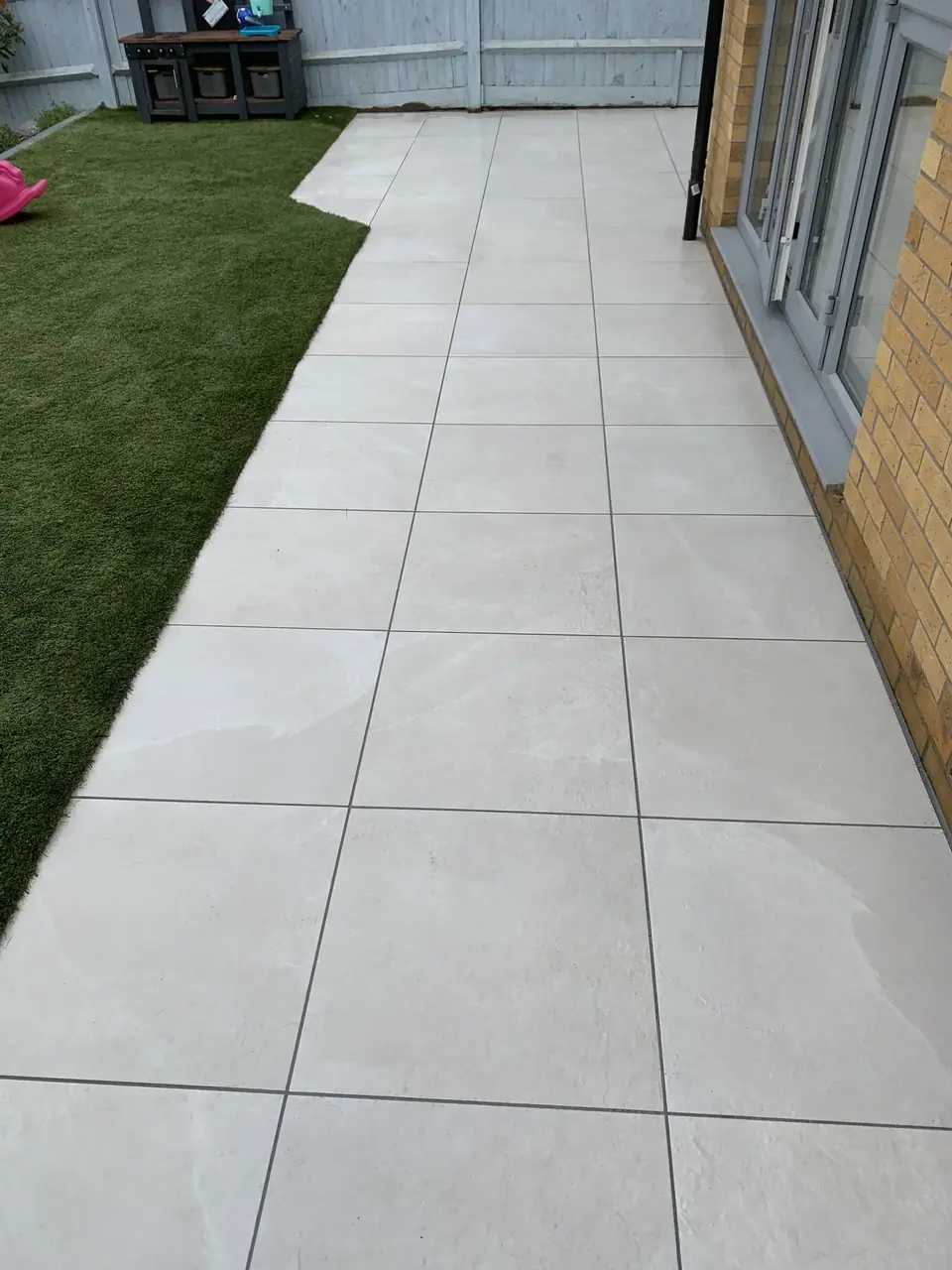 Pale square paving along a brick house beside a lawn